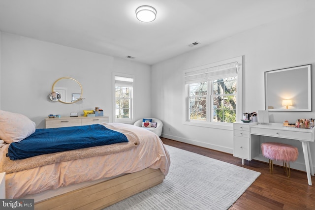 bedroom with dark wood-style floors, visible vents, and baseboards