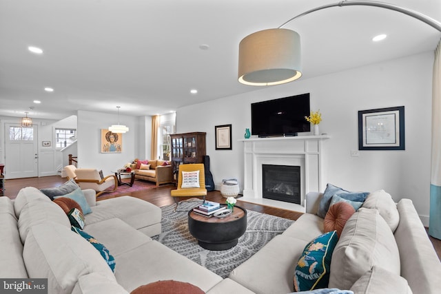 living area with a glass covered fireplace, wood finished floors, and recessed lighting