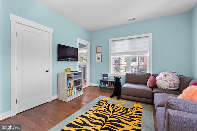 living room featuring dark wood-style flooring, visible vents, and baseboards