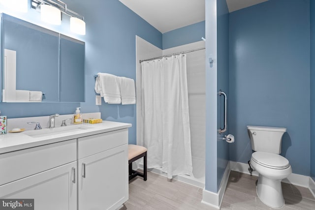 full bath featuring baseboards, a shower stall, toilet, and vanity