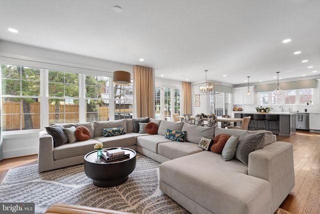 living area with a chandelier, light wood-type flooring, and recessed lighting