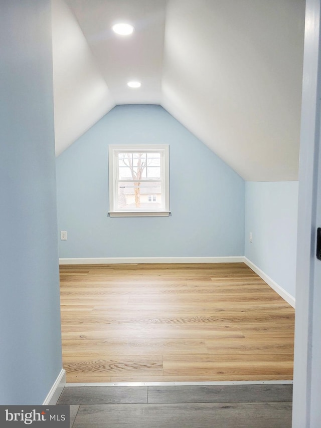 additional living space with hardwood / wood-style floors and lofted ceiling