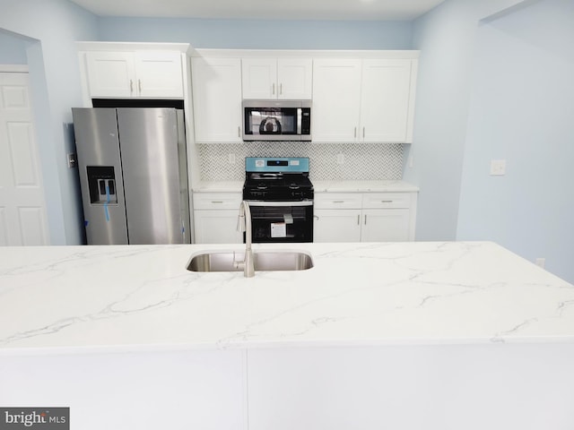 kitchen with sink, appliances with stainless steel finishes, white cabinetry, and tasteful backsplash