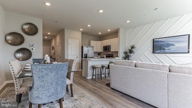 dining space with baseboards, light wood-style flooring, and recessed lighting