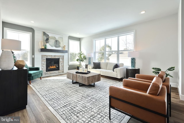 living area with baseboards, a stone fireplace, wood finished floors, and recessed lighting