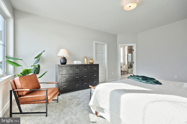 bedroom with light colored carpet, ensuite bath, and baseboards