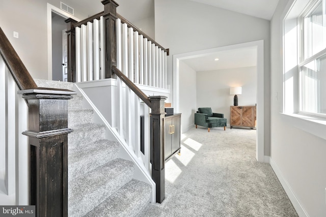 stairs featuring carpet floors, lofted ceiling, visible vents, and baseboards