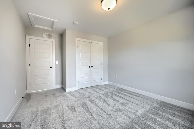 unfurnished bedroom with light carpet, attic access, baseboards, visible vents, and a closet