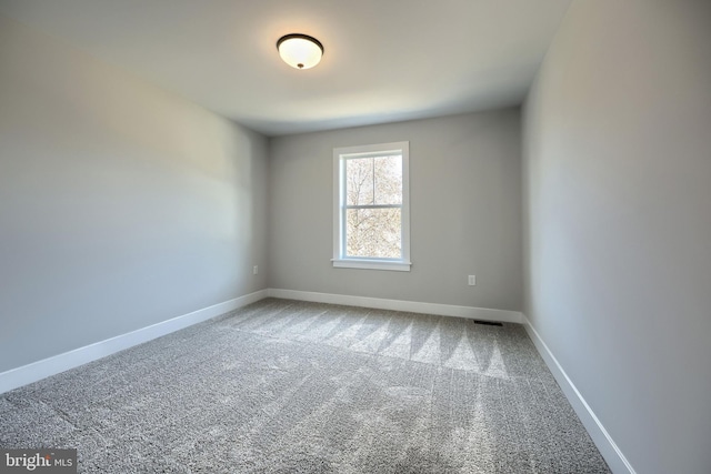 empty room with carpet, visible vents, and baseboards