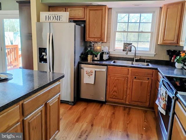 kitchen with sink, backsplash, light hardwood / wood-style flooring, and appliances with stainless steel finishes