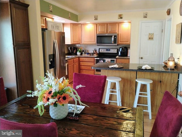 kitchen featuring a kitchen bar, crown molding, tasteful backsplash, wood-type flooring, and stainless steel appliances