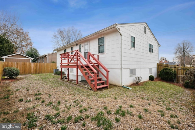 back of property with a fenced backyard and central AC