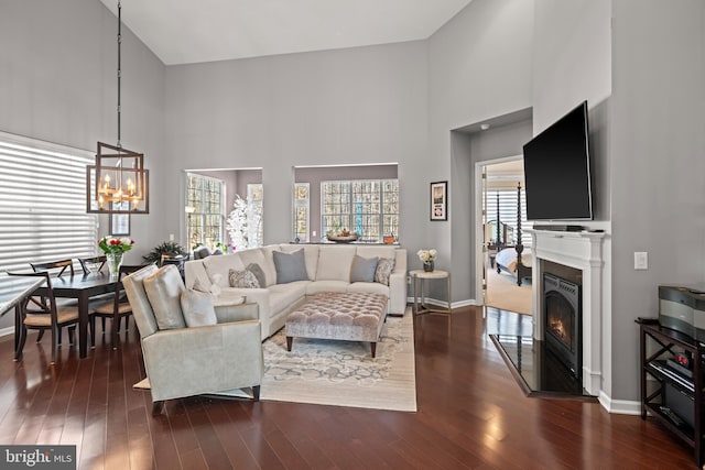 living room with a high ceiling, dark hardwood / wood-style floors, and an inviting chandelier