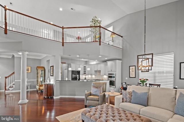 living room featuring a chandelier, dark wood-type flooring, and decorative columns