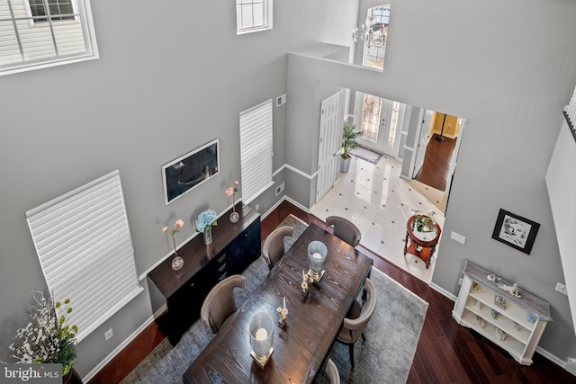 living room featuring dark hardwood / wood-style floors, a towering ceiling, and an inviting chandelier