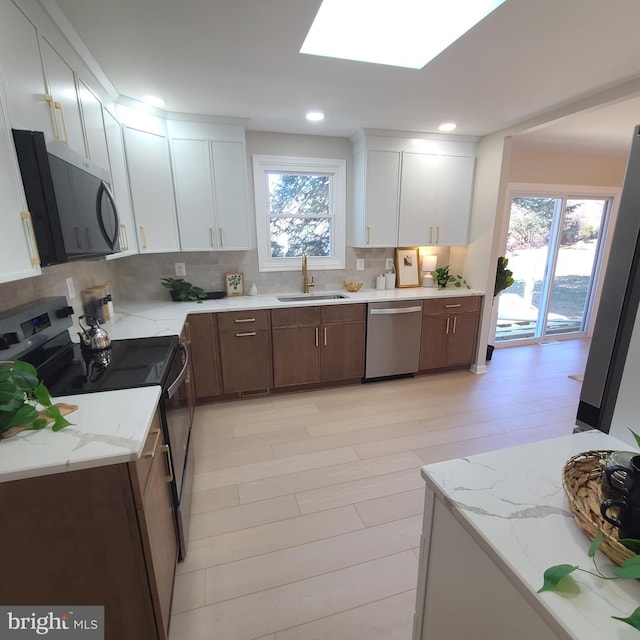 kitchen featuring a skylight, a healthy amount of sunlight, appliances with stainless steel finishes, and a sink