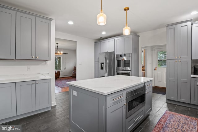 kitchen featuring gray cabinets, appliances with stainless steel finishes, hanging light fixtures, and light stone counters