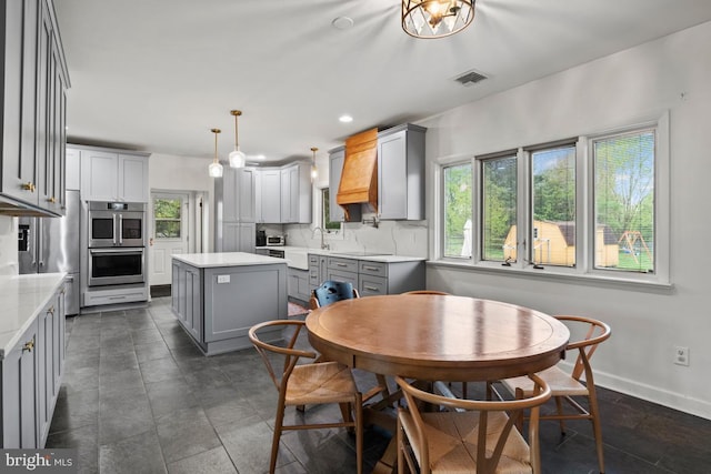 kitchen featuring gray cabinetry, tasteful backsplash, decorative light fixtures, a center island, and double oven