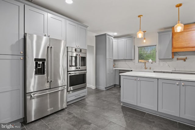 kitchen with gray cabinetry, hanging light fixtures, decorative backsplash, and stainless steel appliances