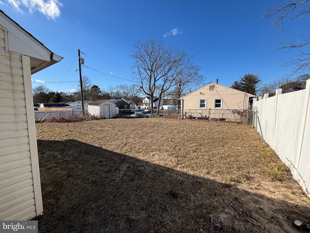 view of yard featuring a storage shed, a fenced backyard, and an outdoor structure