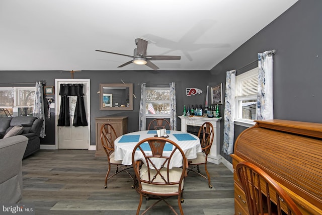 dining space featuring ceiling fan, dark wood-style flooring, a fireplace, and baseboards