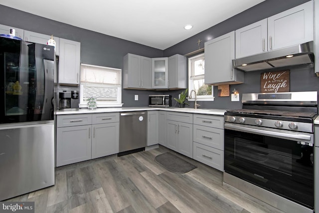 kitchen with light countertops, appliances with stainless steel finishes, wood finished floors, and under cabinet range hood