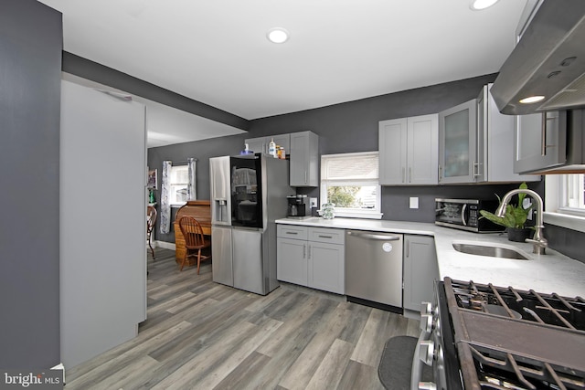 kitchen with extractor fan, appliances with stainless steel finishes, light countertops, and gray cabinetry