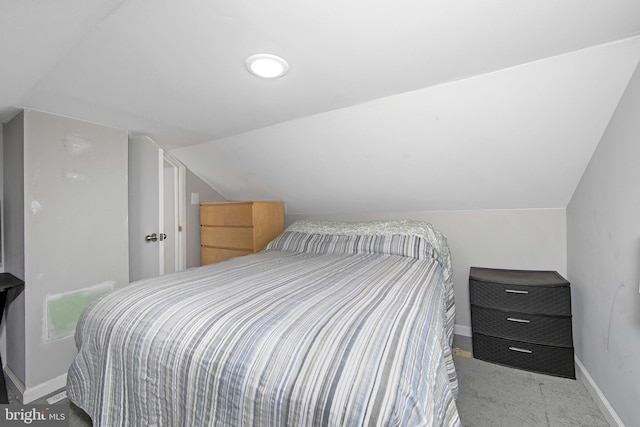 bedroom featuring light colored carpet, vaulted ceiling, and baseboards