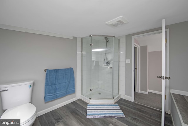 bathroom with toilet, wood finished floors, visible vents, baseboards, and a shower stall