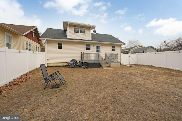 rear view of property with a gate, a fenced backyard, and a deck