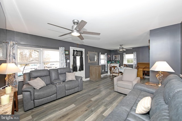 living room with wood finished floors, a ceiling fan, and baseboards