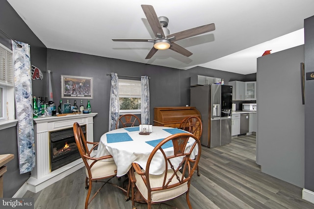 dining room with ceiling fan, wood finished floors, and a glass covered fireplace