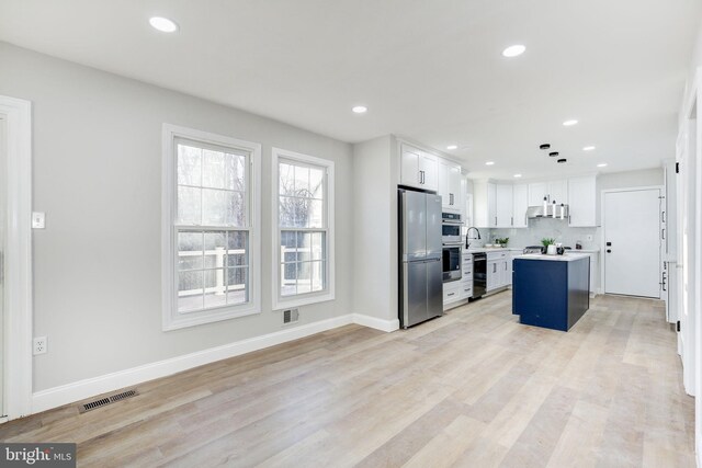 kitchen with visible vents, a kitchen island, stainless steel appliances, light countertops, and light wood-type flooring