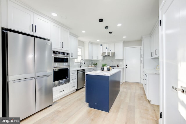 kitchen with appliances with stainless steel finishes, a center island, white cabinetry, and light wood-style floors