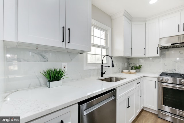 kitchen featuring tasteful backsplash, white cabinets, appliances with stainless steel finishes, extractor fan, and a sink