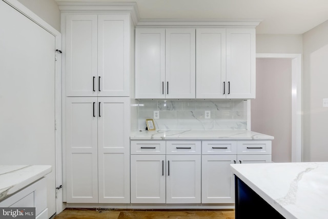 kitchen featuring backsplash, white cabinetry, and light stone countertops