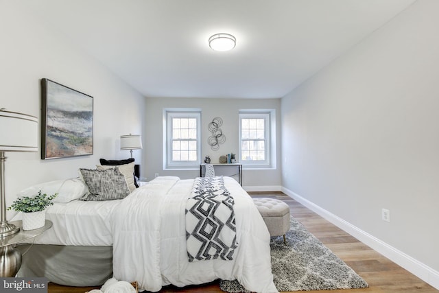 bedroom featuring light wood finished floors and baseboards