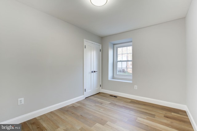 spare room with light wood-style floors, baseboards, and visible vents