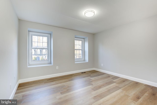 spare room featuring visible vents, light wood-style flooring, and baseboards