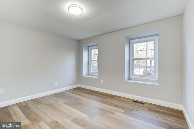 unfurnished room with baseboards, a healthy amount of sunlight, visible vents, and light wood finished floors