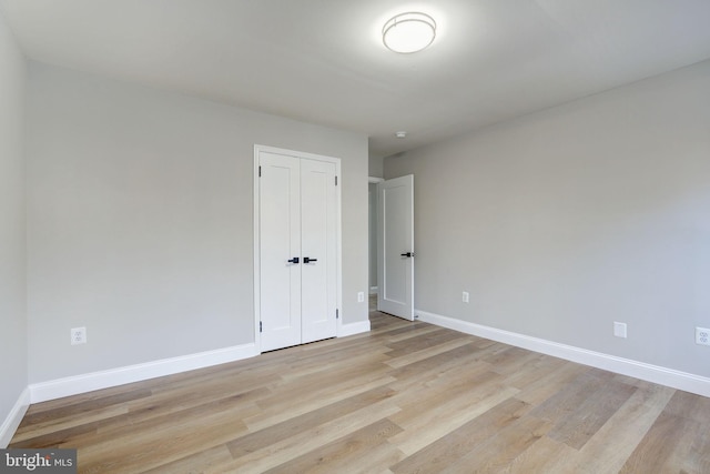 unfurnished bedroom featuring light wood-style floors, a closet, and baseboards