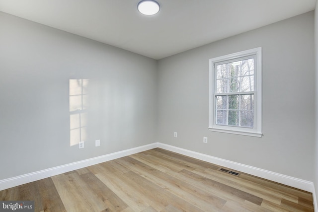 spare room featuring light wood-style flooring, visible vents, and baseboards