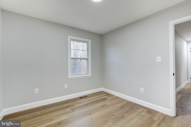 unfurnished room featuring light wood-style flooring, visible vents, and baseboards