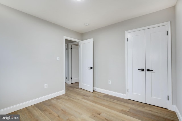 unfurnished bedroom featuring a closet, wood finished floors, and baseboards