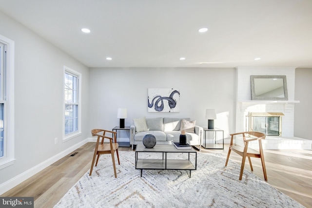 living room featuring recessed lighting, a fireplace, baseboards, and wood finished floors