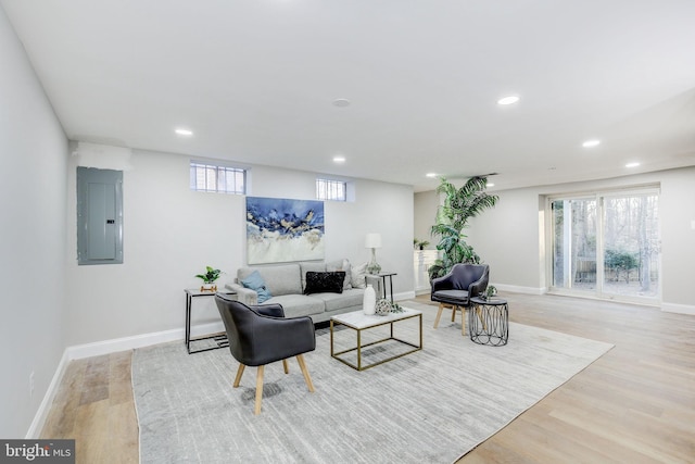 living area featuring light wood finished floors, electric panel, baseboards, and recessed lighting