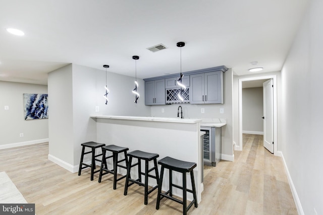 kitchen featuring light wood-style floors, a kitchen bar, visible vents, and light countertops