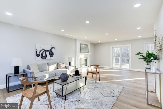 living area with baseboards, recessed lighting, a fireplace, and light wood-style floors