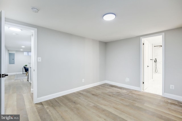 unfurnished room with light wood-style floors, electric panel, and baseboards