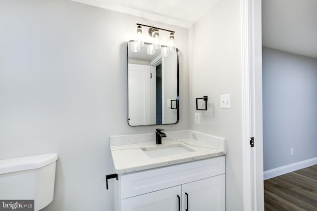 half bath with baseboards, vanity, toilet, and wood finished floors